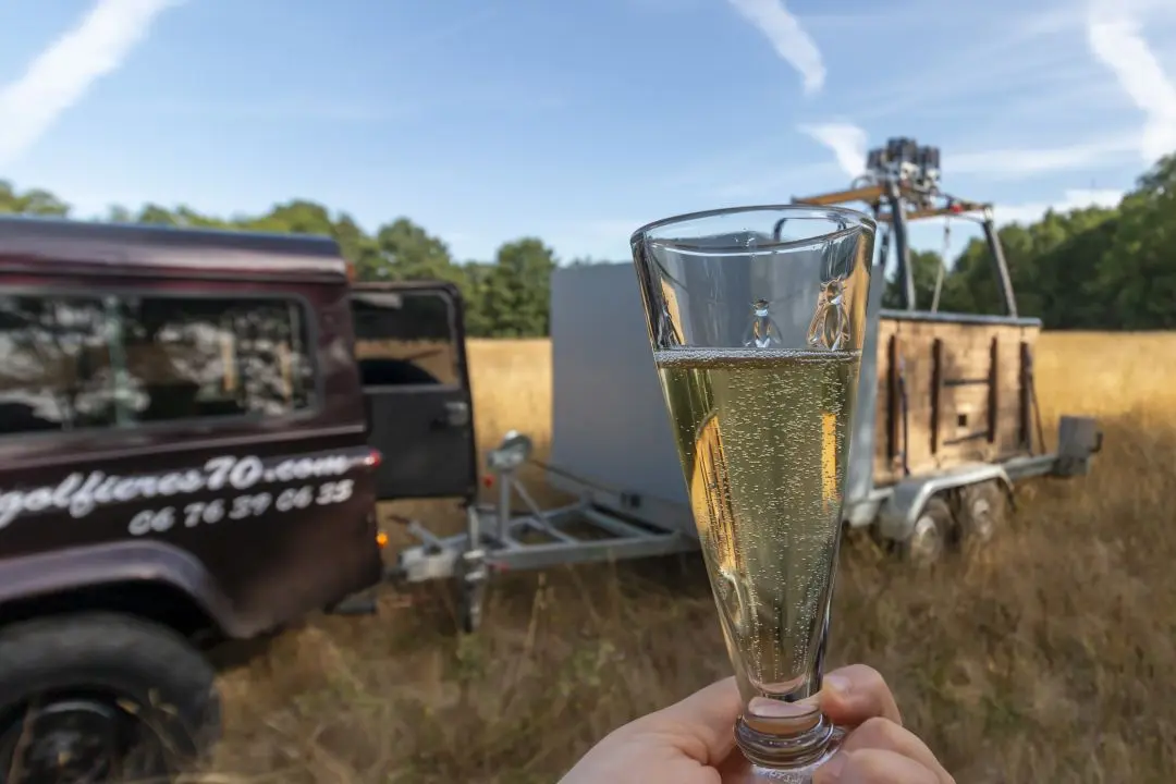 Une coupe de champagne devant une nacelle de montgolfière